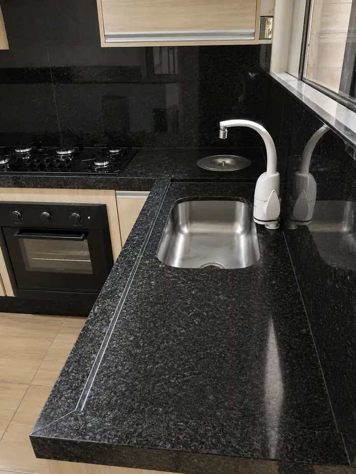 Cozinha em L com bancada de granito escuro e cuba inox
